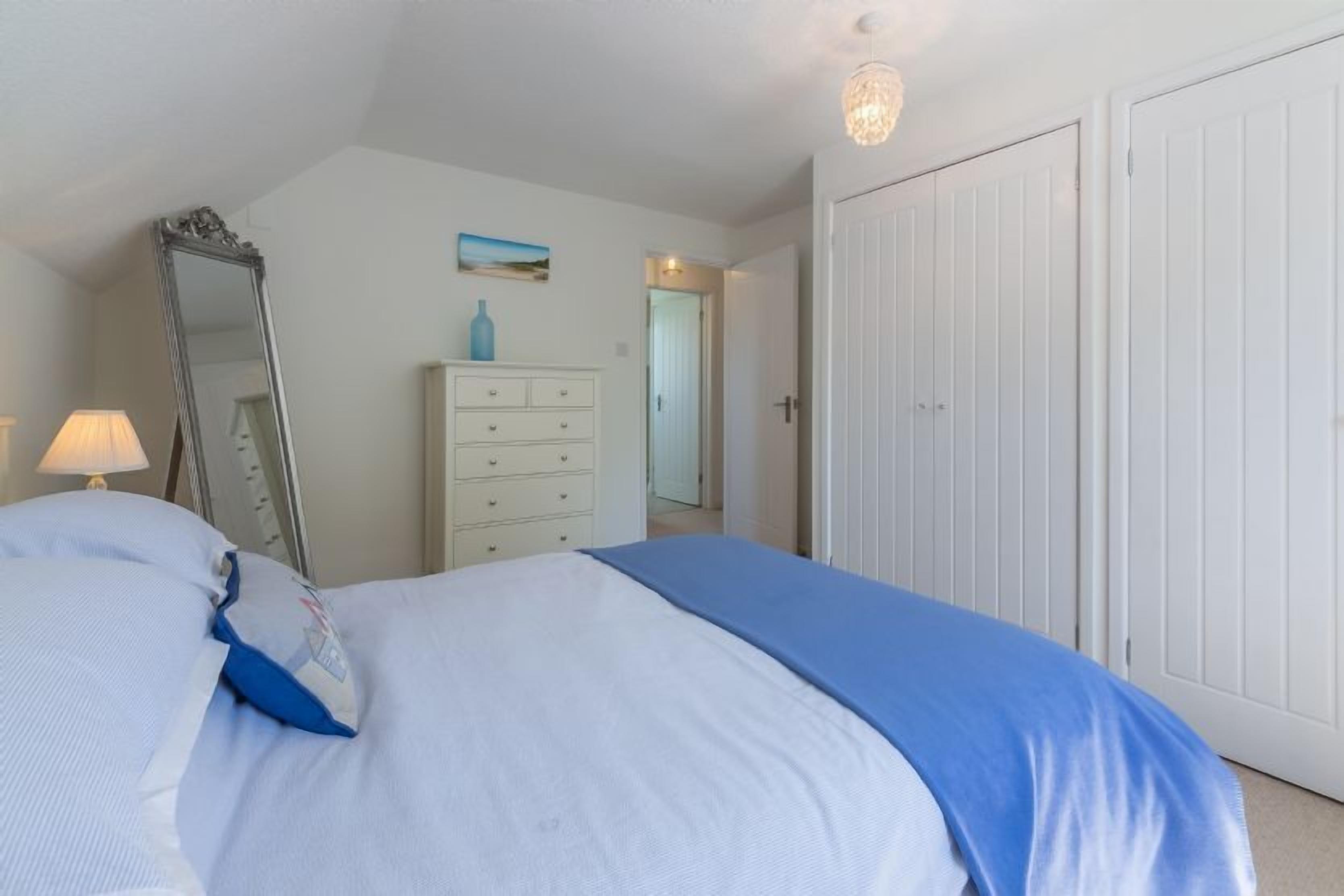 A bedroom with a bed, a dresser, a mirror, and a door.