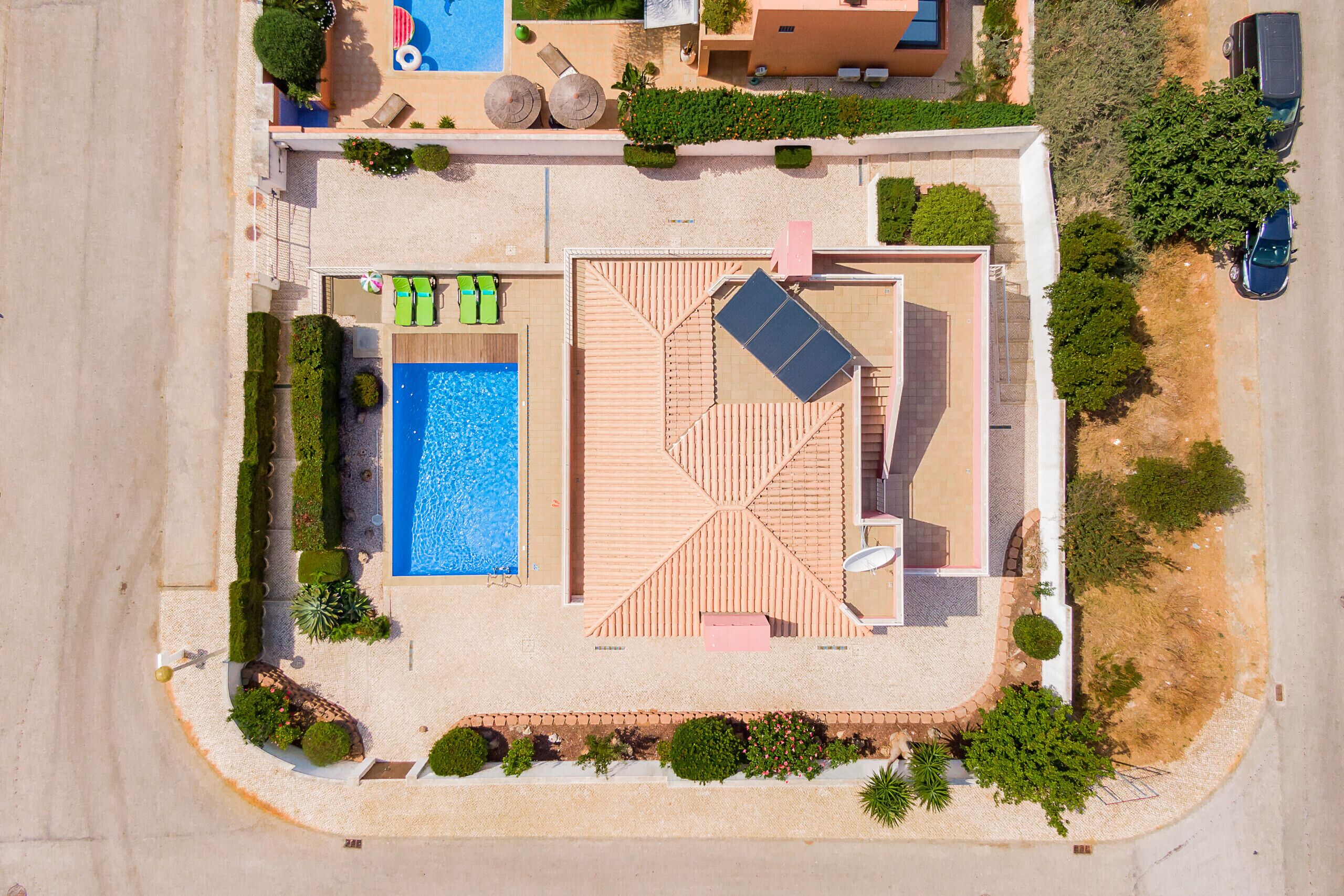 Vue aérienne d’un complexe hôtelier doté d’une piscine, de chaises longues, d’une terrasse sur le toit et d’un parking.