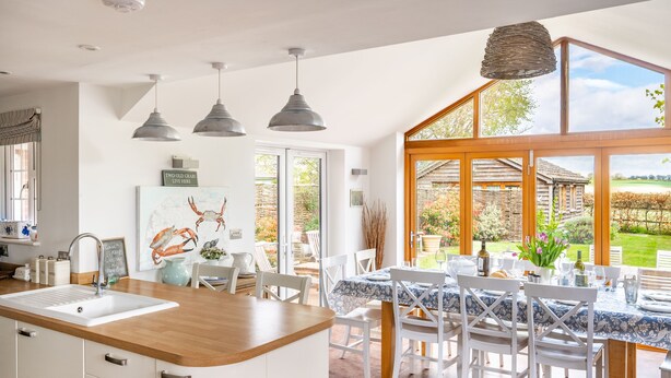 A kitchen with a large island, white cabinetry, and a view of the garden through large windows.