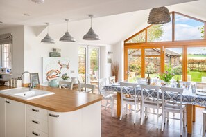 A kitchen with a large island, white cabinetry, and a view of the garden through large windows.