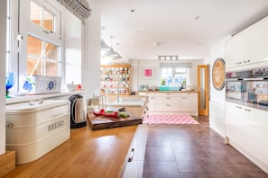 A modern kitchen with a central island, white cabinetry, and a large window.