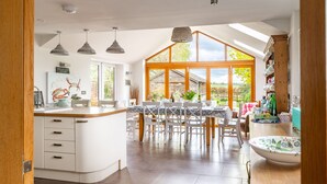 A modern kitchen with a large island, white cabinetry, and a dining area with a table and chairs.