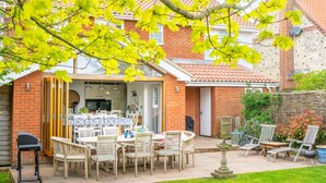 A patio with outdoor furniture, a barbecue grill, and a dining table with chairs.