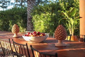 A table with a bowl of fruit, two pineapple-shaped vases, and chairs. - TD Villa Marinesca Typical Villa with Pool (Conversano)