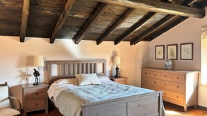 A bedroom with a wooden ceiling, a bed with a headboard, bedside tables, a dresser, and framed artwork on the wall. - Etxetxobarri, a single-family farmhouse with views of the Anboto mountain range. (Mallabia - bizkaia)