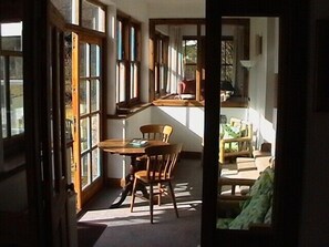 Une pièce avec une table et des chaises en bois, de grandes fenêtres et une vue sur l’extérieur.
