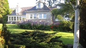 A large house with a well-maintained garden, including a rock garden and various shrubs.