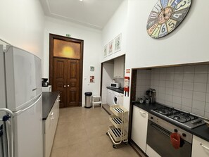 Een keuken met een koelkast, fornuis, magnetron en een wandklok.