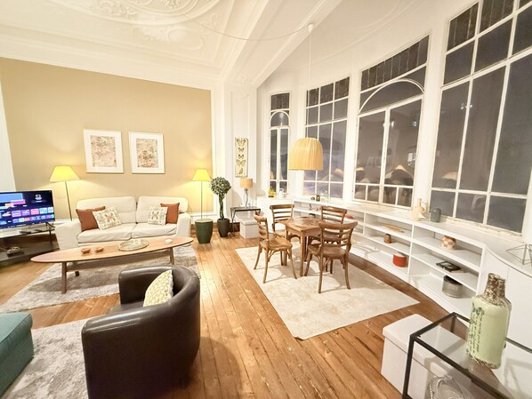 A living room with a sofa, coffee table, and a dining area with chairs and a table.