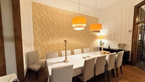 A dining area with a long table, chairs, and two hanging lamps.