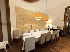 A dining area with a long table, chairs, and hanging lamps.