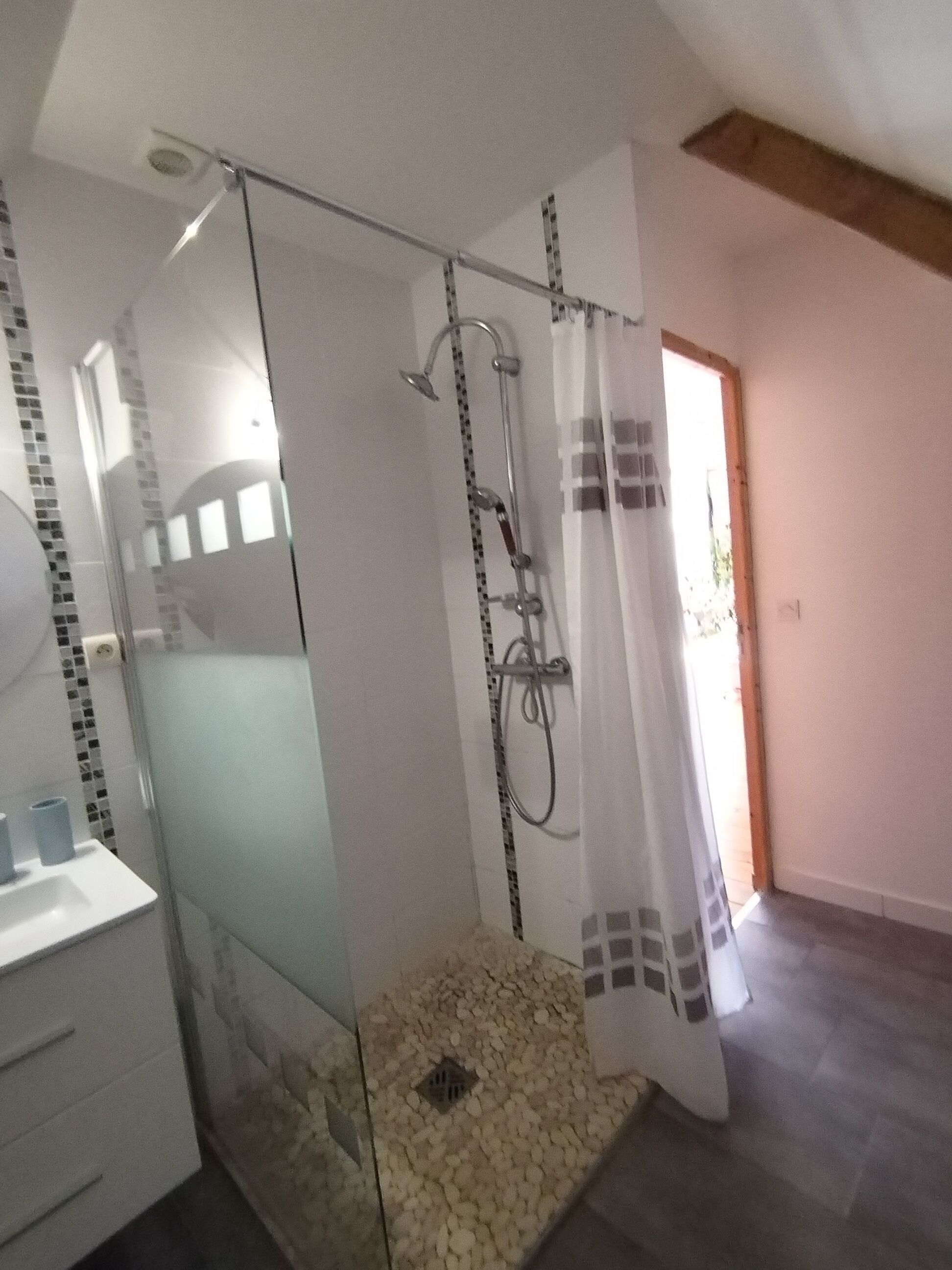 A bathroom with a glass-enclosed shower, a white sink, and a tiled floor.
