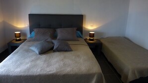 Ein Doppelbett mit Kopfteil, zwei Nachttische mit Lampen und ein Einzelbett im angrenzenden Zimmer.