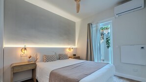 A modern bedroom with a large bed, bedside tables, a ceiling fan, and a view of greenery outside. - House 80 m from the beach, garden, swimming pool, barbecue and Wifi Ideal for families. (Marbella)
