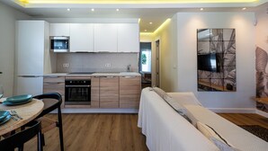 A compact kitchen with modern appliances, a dining area with a table set for two, and a bedroom with a bed and a large artwork on the wall. - House 80 m from the beach, garden, swimming pool, barbecue and Wifi Ideal for families. (Marbella)