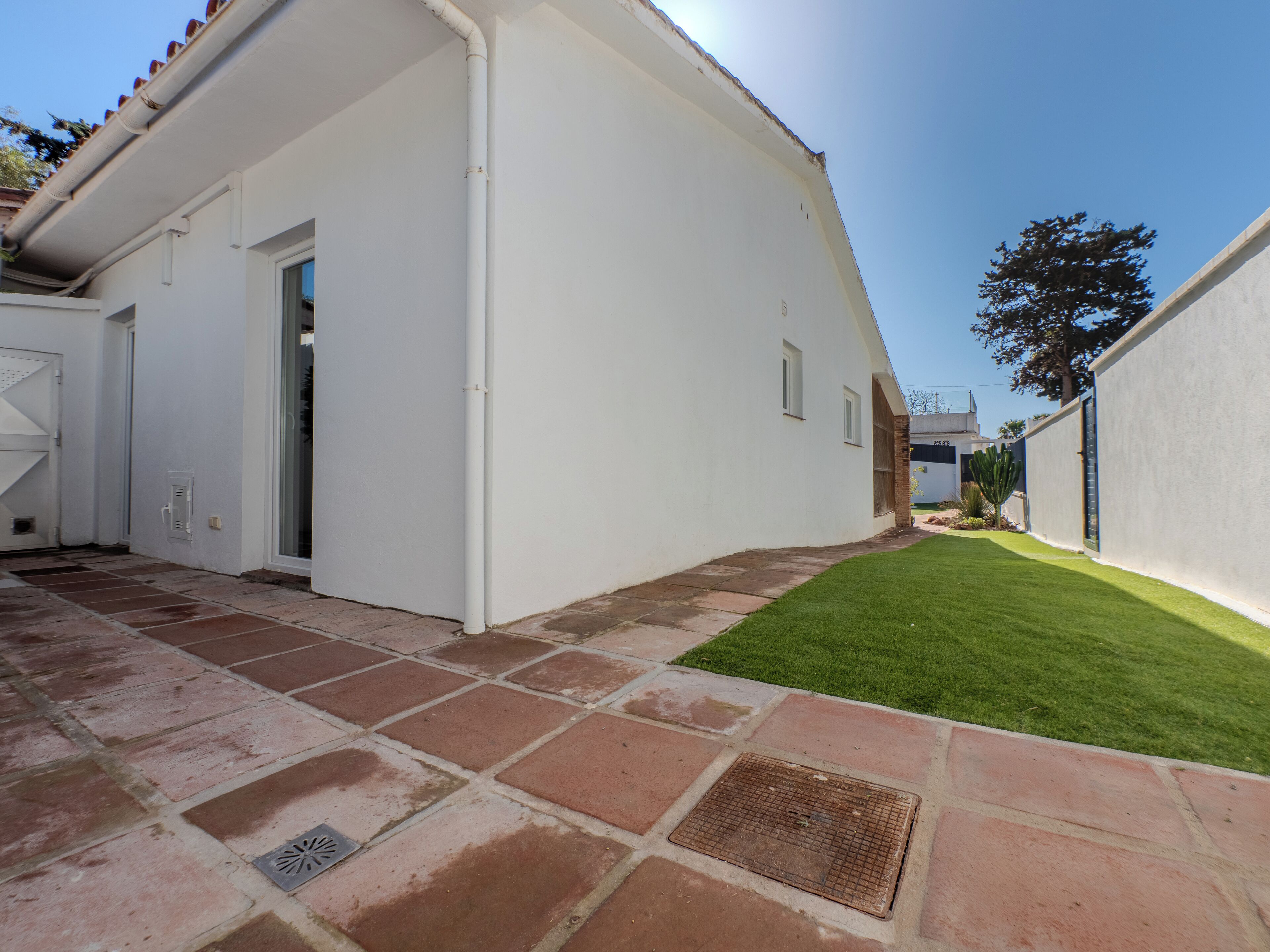 A white building with a tiled patio and a small lawn.