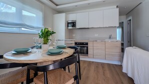A modern kitchen with white cabinets, a built-in oven, and a dining area with a round table and chairs. - House 80 m from the beach, garden, swimming pool, barbecue and Wifi Ideal for families. (Marbella)