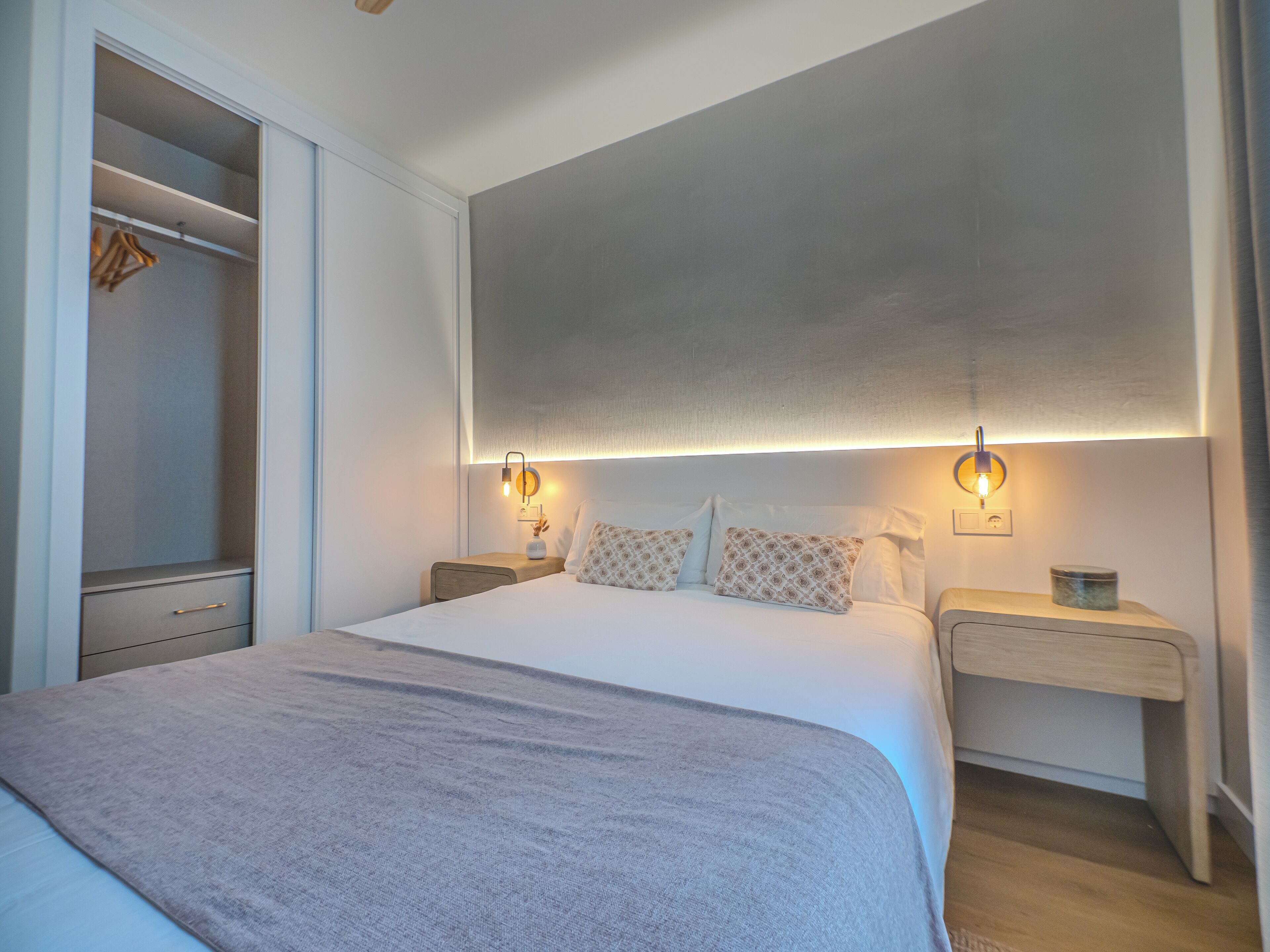 Quarto com cama grande, mesas de cabeceira, guarda-roupa e luminária no teto.