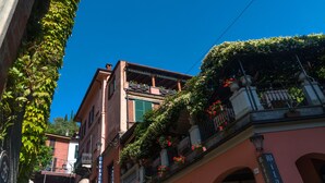 A building with a balcony covered in greenery and flowers, a visible sign indicating a restaurant, and a clear blue sky. - BELLAGIO'S SUNSET, appt with terrace and view of the lake in  Bellagio (Bellagio)