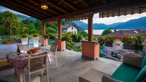 A covered patio with wicker furniture, a table with a fruit bowl, and potted plants. - BELLAGIO'S SUNSET, appt with terrace and view of the lake in  Bellagio (Bellagio)