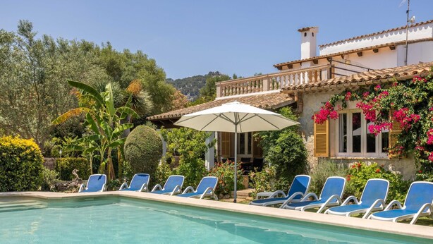 A pool area with blue lounge chairs and a white umbrella. - Villa Can Boseta by SunVillas Mallorca (Pollença)