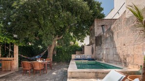 Un espace piscine aménagé avec des chaises longues, un hamac et un ensemble de mobilier de jardin.