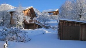 Et snødekt træhus med balkon og garage.