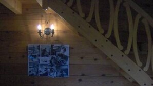 Et hyggeligt værelse med trælofter, en rød sofa, et bord med blåt dug og en vægmonteret lampe.