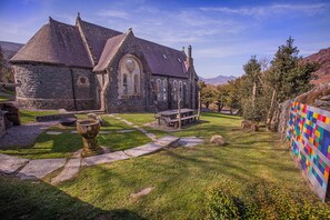 Une église en pierre avec un banc en pierre et une courtepointe aux couleurs vives accrochée à un mur.
