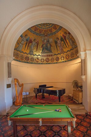 Une pièce équipée d’une table de billard, d’un piano et d’une harpe.