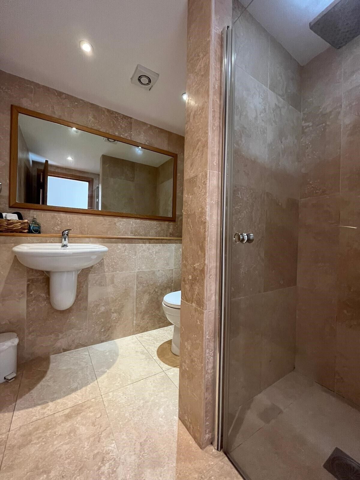 A bathroom with a sink, toilet, and glass shower enclosure.