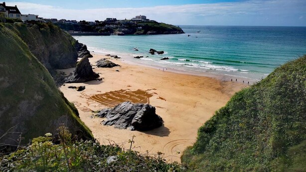 A coastal beach with rocky outcrops and a clear view of the sea.