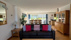 A living room with a black sofa, wooden coffee table, and a dining area with a table and chairs.