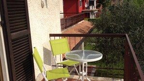 A balcony with a table and two chairs, a railing, and a view of neighboring buildings. - Modern apartment, Residence with swimming pool surrounded by greenery with FREE Wi-Fi (Sirmione)