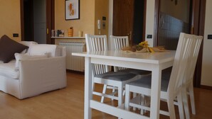 A dining area with a white table and chairs, a white sofa, and a radiator. - Modern apartment, Residence with swimming pool surrounded by greenery with FREE Wi-Fi (Sirmione)