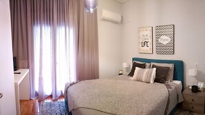 A bedroom with a bed, bedside tables, a desk, and curtains.