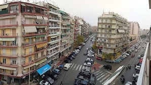 A multi-story residential building with balconies, a street view, and parked cars.