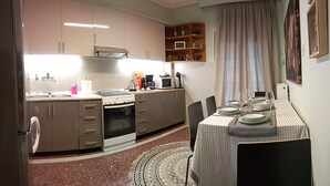 A compact kitchen with a dining area, equipped with a stove, microwave, and coffee maker.