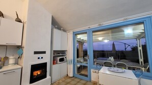 Una cucina compatta con piano cottura integrato, forno a microonde e un piccolo spazio pranzo con tavolo e sedie.