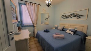 Una camera da letto con un letto, una cassettiera, una finestra con tende, uno specchio e un'opera d'arte a parete.