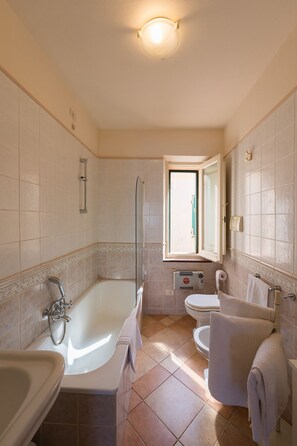 A bathroom with a bathtub, a shower, a sink, and a toilet. - Apartment with terrace and view of the sea (Alghero)