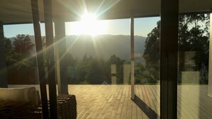 A sunlit balcony with a view of distant mountains and trees.
