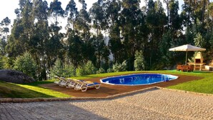 A swimming pool with lounge chairs and a barbecue area surrounded by trees.