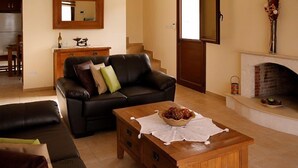 Un soggiorno con un divano in pelle, un tavolino in legno, un camino e, sullo sfondo, un'area pranzo.