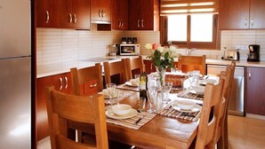 Una cucina con mobili in legno, un tavolo da pranzo per sei persone e una finestra con persiane.