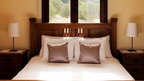 Un letto rifatto con due cuscini, una testata in legno e una finestra con vista su del verde.