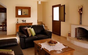 A living room with a leather sofa, a wooden coffee table, a fireplace, and a dining area in the background.