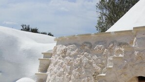 Uma escadaria de pedra que leva a uma porta com portão de metal, e vários almofadas colocadas nos degraus.
