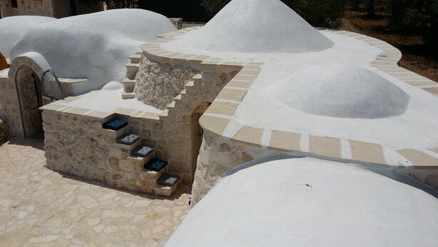 Uma construção de pedra com design circular e uma pequena escadaria que leva a uma plataforma.