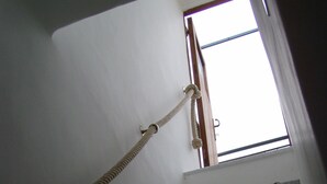 Eine Treppe mit Seil an der Handlauf, die zu einem Fenster mit Blick auf den Himmel führt.